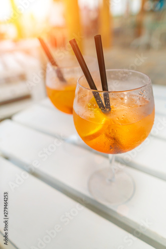 Delicious classic iced aperol spritz cocktail with ice cubes on a hot tropical beach in summer sunshine