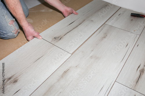 Worker making laminate flooring in apartment. Maintenance repair renovation. Wooden parquet planks indoors.