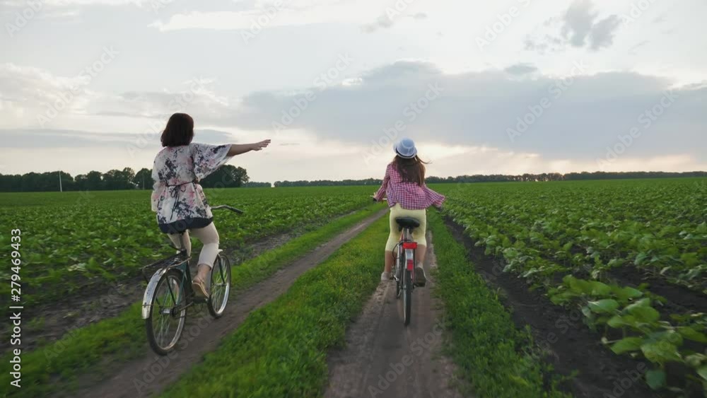Mother with daughter on bicycles rides on a dirt road Mother with daughter on bicycles rides on a dirt road