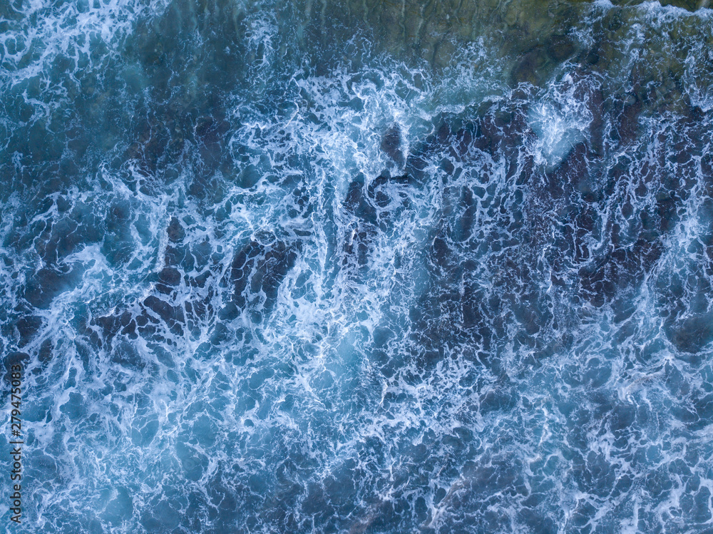 Above the ocean, aerial view at the waves and surface near coast line