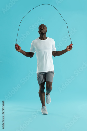 Workout. Sports man in sportswear exercising on jumping rope photo