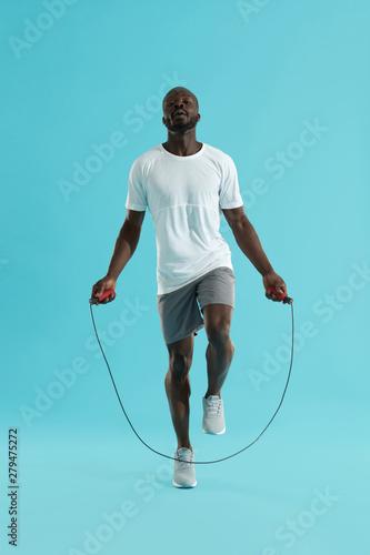 Workout. Sports man in sportswear exercising on jumping rope © puhhha