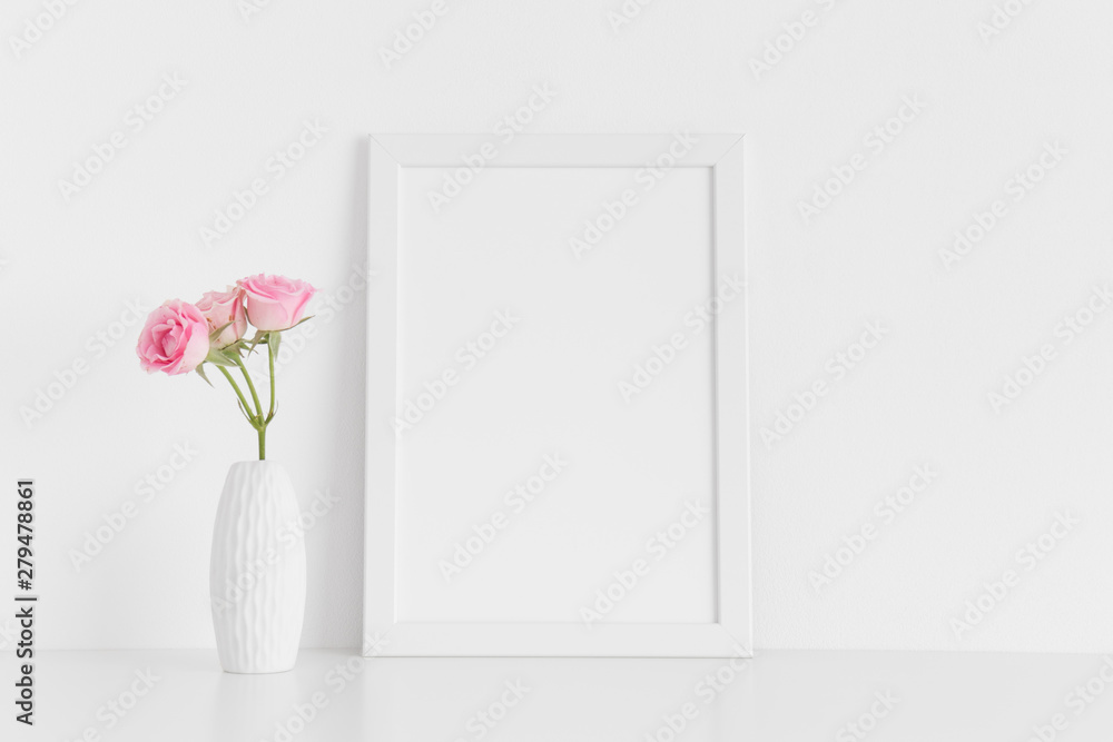 White frame mockup with pink roses in a vase on a white table.Portrait orientation. - obrazy, fototapety, plakaty 
