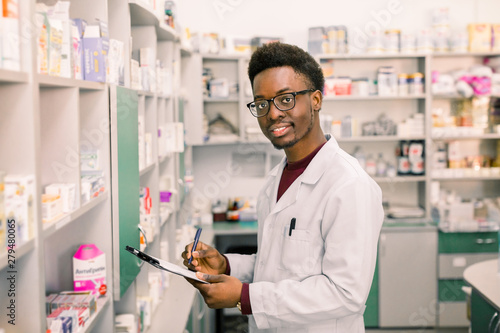 Картината върху платно Smiling African American man pharmacist or Chemist Writing On Clipboard While st