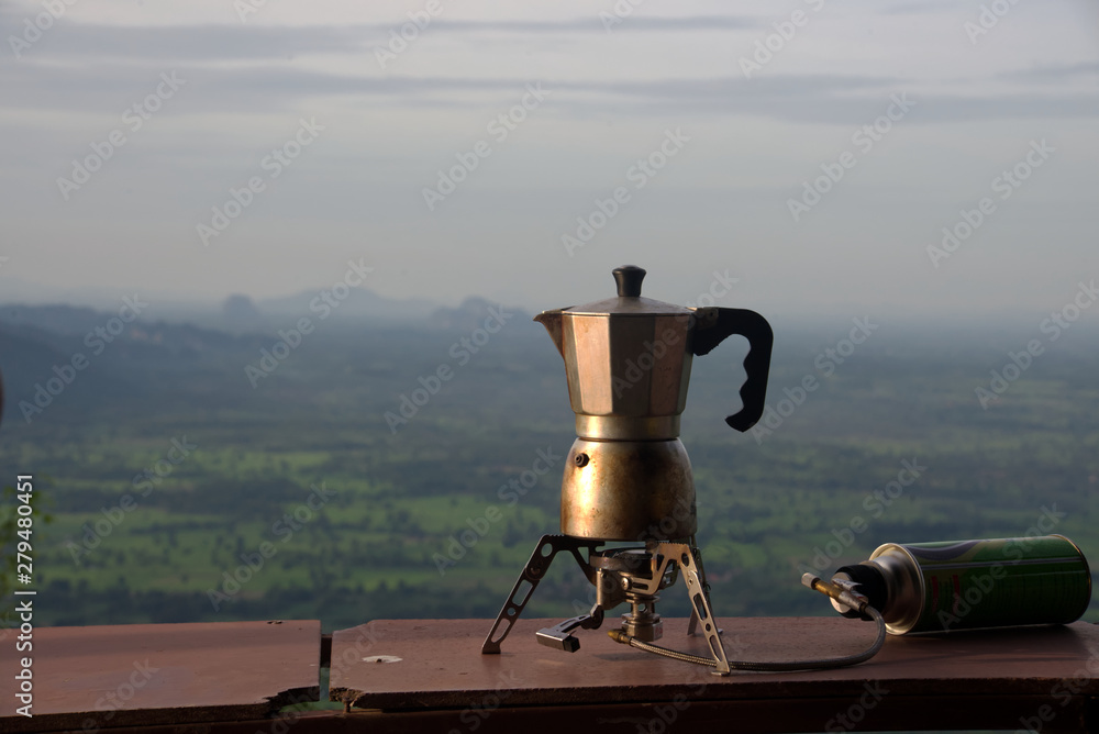A brown coffee maker with blur green forest background in a morning