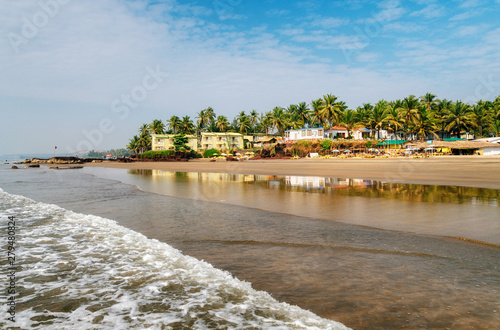 Guesthouses and sunbeds on beach of Arabian Sea in middle of rocks and sandstone in Ashvem, Goa, India