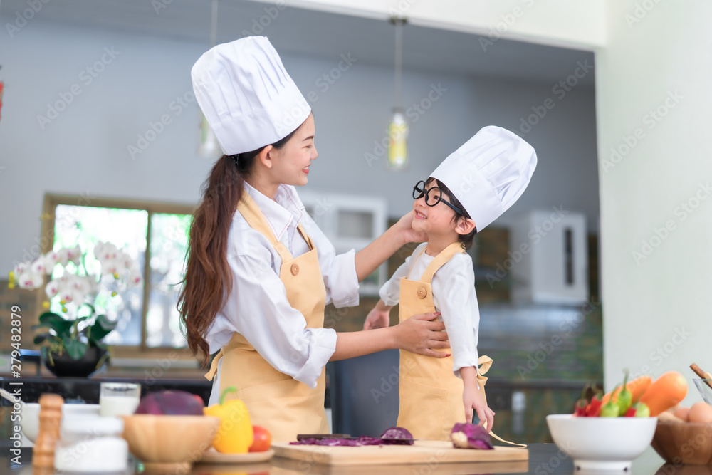 Professional Chef asian mom dressed up little son ready teaching cooking salad vegetable knowledge prepare healthy food in the kitchen room for dinner at home happy family lifestyle. Professional Chef asian mom dressed up little son ready teaching cooking salad vegetable knowledge prepare healthy food in the kitchen room for dinner at home happy family lifestyle.