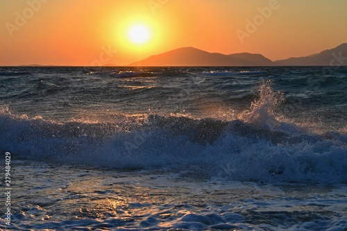 Beautiful sunset with sea and waves. Natural colorful background. Concept for summer and sea vacation. Greece - island of Kos.