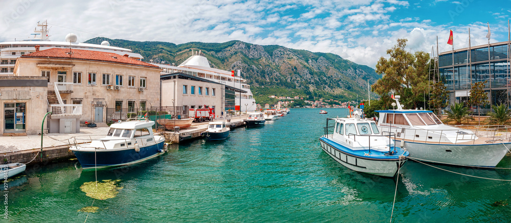 Boats in the water at harbor in the ancient town Kotor surrounded by mountains, Montenegro. Panoramic view