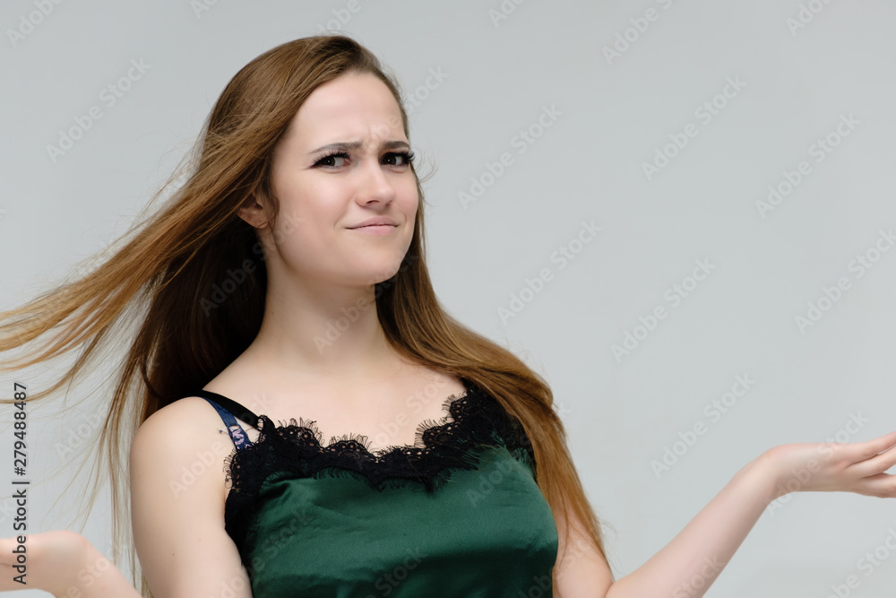 Concept close-up portrait of a pretty girl, young woman with long beautiful brown hair in a green t-shirt on a white background. In the studio in different poses showing emotions. Concept close-up portrait of a pretty girl, young woman with long beautiful brown hair in a green t-shirt on a white background. In the studio in different poses showing emotions.