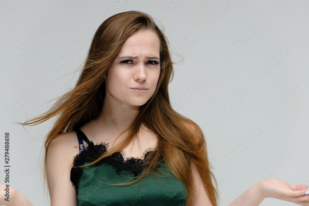 Concept close-up portrait of a pretty girl, young woman with long beautiful brown hair in a green t-shirt on a white background. In the studio in different poses showing emotions. Concept close-up portrait of a pretty girl, young woman with long beautiful brown hair in a green t-shirt on a white background. In the studio in different poses showing emotions.