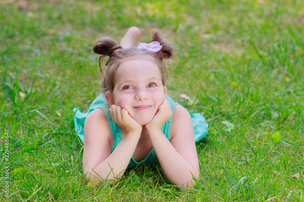 Cute girl lying on the green grass, outdoors, summer time, blurred background Cute girl lying on the green grass, outdoors, summer time, blurred background