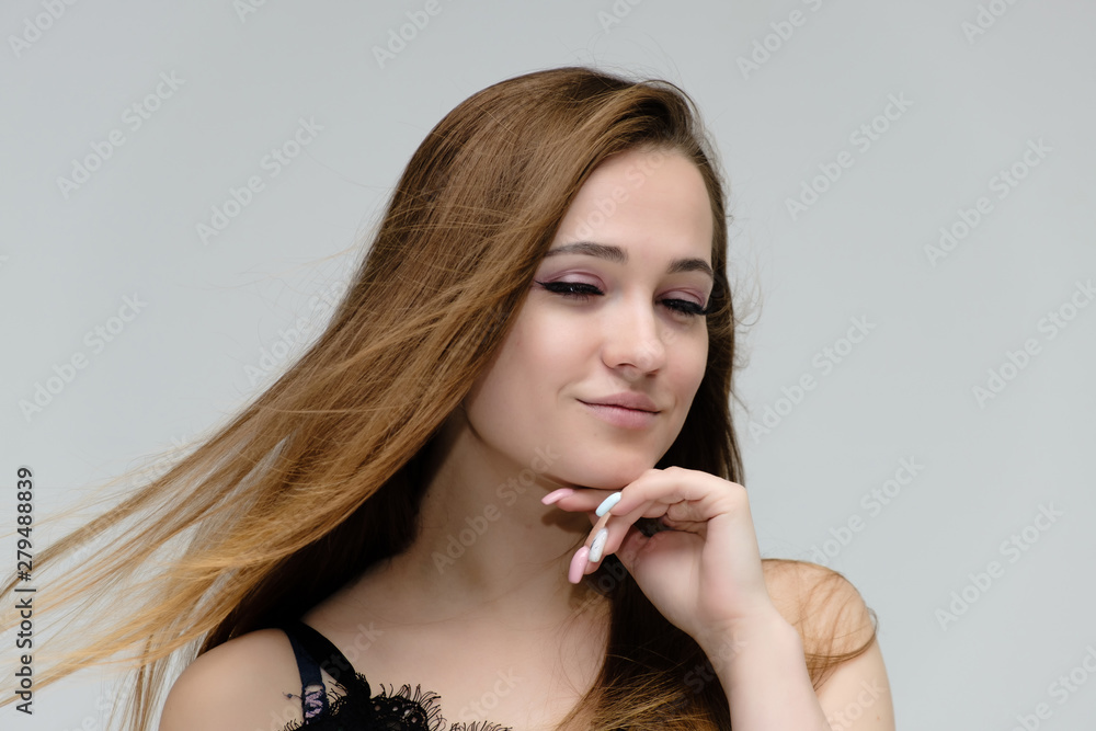 Concept close-up portrait of a pretty girl, young woman with long beautiful brown hair and beautiful face skin on a white background. In the studio in different poses showing emotions.