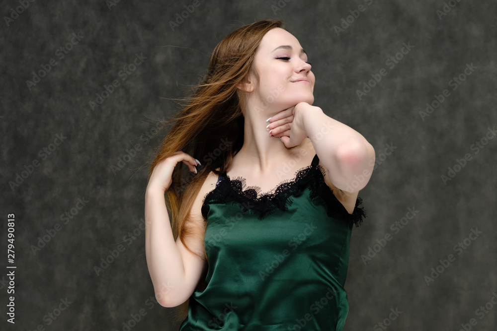 Concept portrait of the waist of a pretty girl, a young woman with long beautiful brown hair and a green T-shirt on a gray background. In the studio in different poses showing emotions. Concept portrait of the waist of a pretty girl, a young woman with long beautiful brown hair and a green T-shirt on a gray background. In the studio in different poses showing emotions.