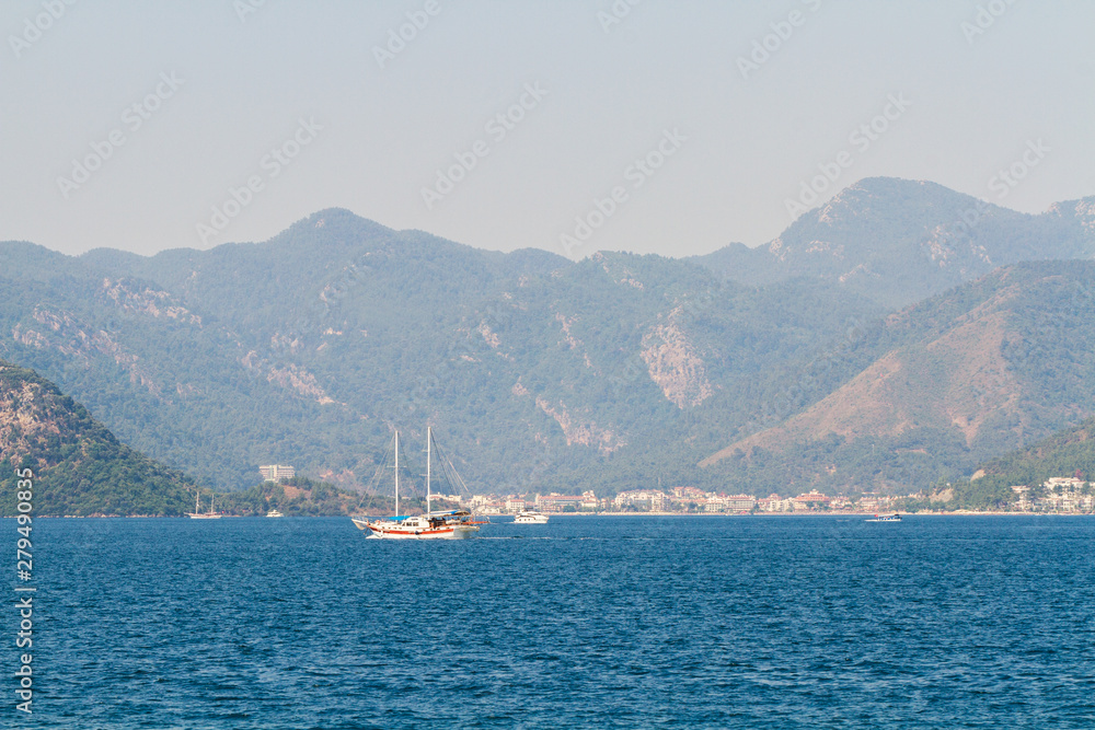 Boat on the background of mountains overgrown with forest.