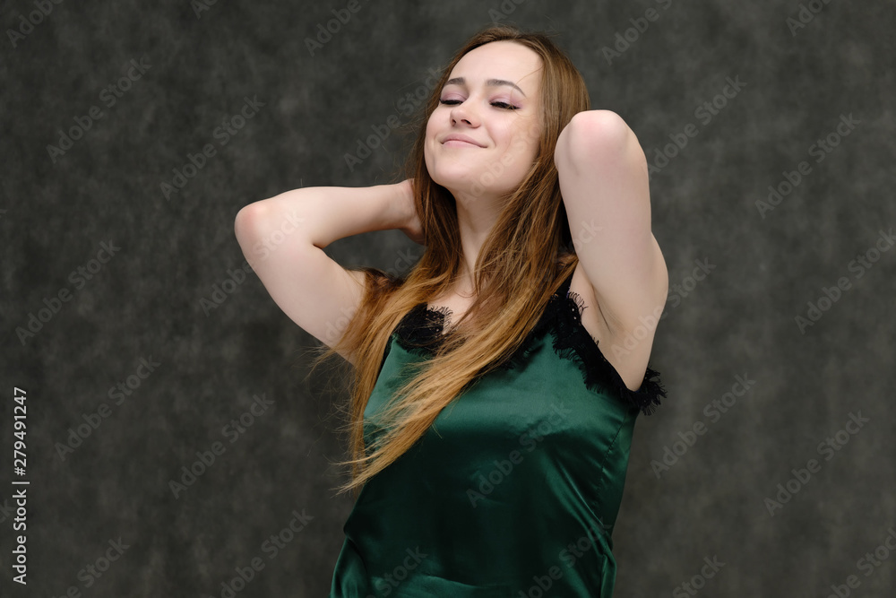Concept portrait of the waist of a pretty girl, a young woman with long beautiful brown hair and a green T-shirt on a gray background. In the studio in different poses showing emotions. Concept portrait of the waist of a pretty girl, a young woman with long beautiful brown hair and a green T-shirt on a gray background. In the studio in different poses showing emotions.