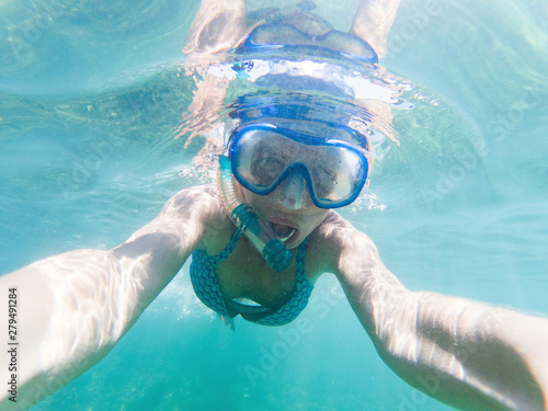 woman taking a selfie snorkeling in clear tropical waters - active holiday