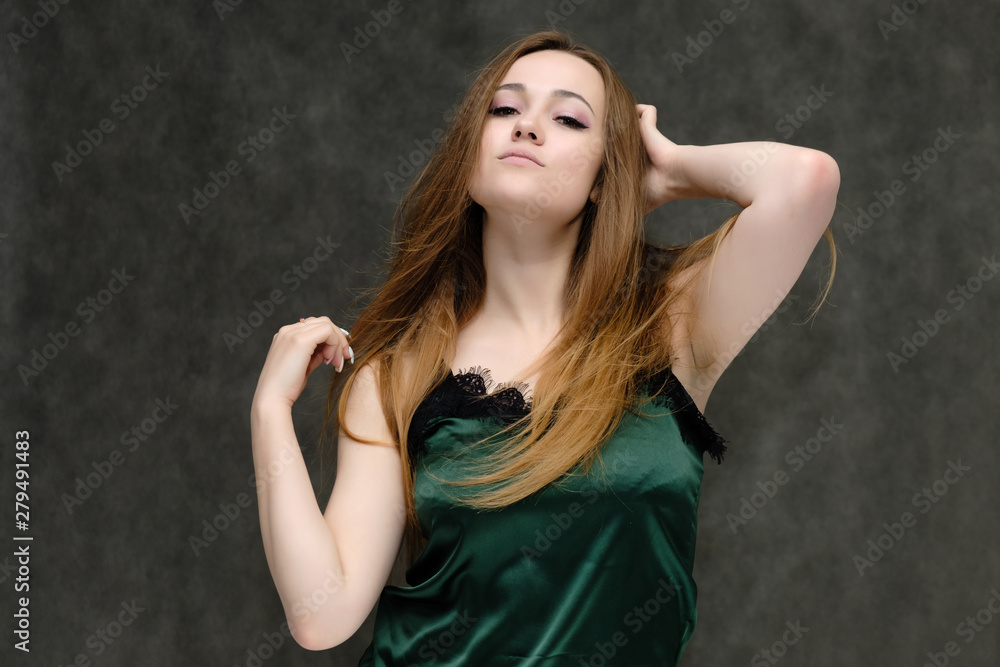 Concept portrait of the waist of a pretty girl, a young woman with long beautiful brown hair and a green T-shirt on a gray background. In the studio in different poses showing emotions. Concept portrait of the waist of a pretty girl, a young woman with long beautiful brown hair and a green T-shirt on a gray background. In the studio in different poses showing emotions.
