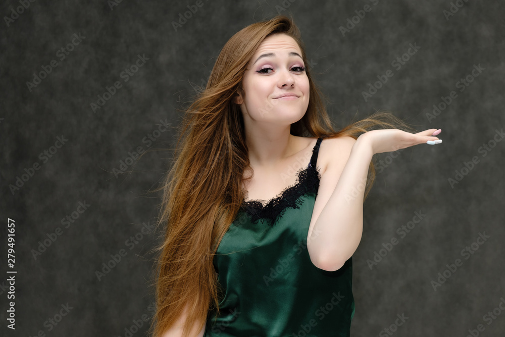 Concept portrait of the waist of a pretty girl, a young woman with long beautiful brown hair and a green T-shirt on a gray background. In the studio in different poses showing emotions. Concept portrait of the waist of a pretty girl, a young woman with long beautiful brown hair and a green T-shirt on a gray background. In the studio in different poses showing emotions.
