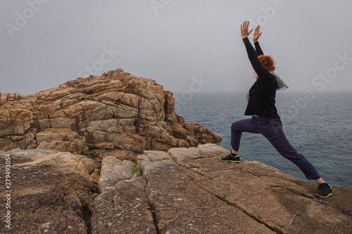 Woman practicing yoga on the coast of Armor