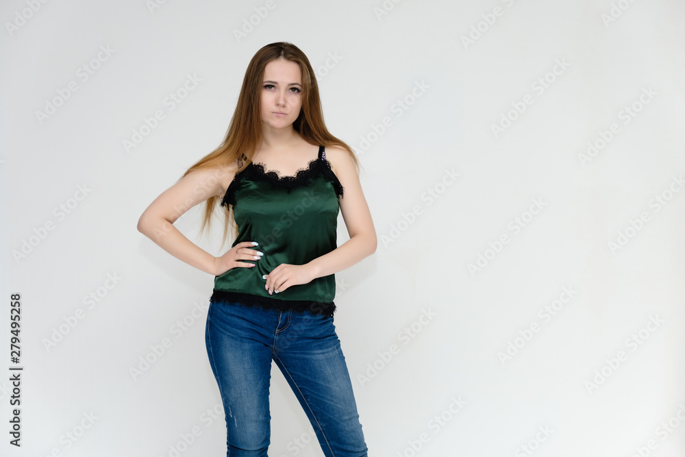 Concept portrait above the knee of a pretty girl, a young woman with long beautiful brown hair and a green t-shirt and blue jeans on a white background. In studio in different poses showing emotions. Concept portrait above the knee of a pretty girl, a young woman with long beautiful brown hair and a green t-shirt and blue jeans on a white background. In studio in different poses showing emotions.
