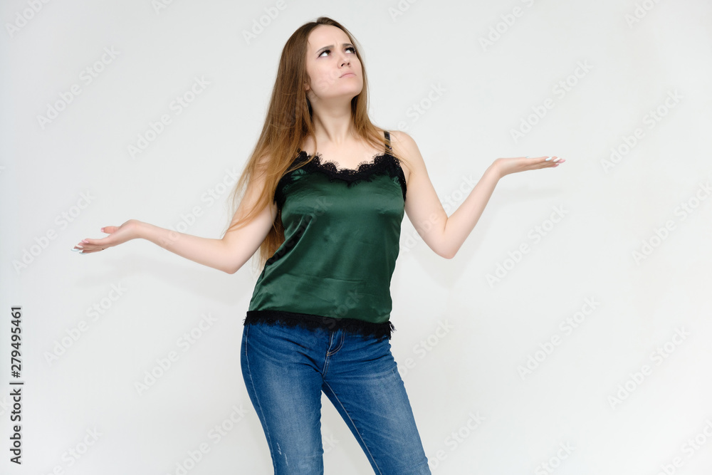 Concept portrait above the knee of a pretty girl, a young woman with long beautiful brown hair and a green t-shirt and blue jeans on a white background. In studio in different poses showing emotions. Concept portrait above the knee of a pretty girl, a young woman with long beautiful brown hair and a green t-shirt and blue jeans on a white background. In studio in different poses showing emotions.