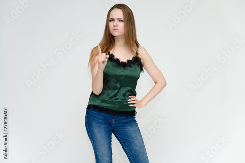 Concept portrait above the knee of a pretty girl, a young woman with long beautiful brown hair and a green t-shirt and blue jeans on a white background. In studio in different poses showing emotions.