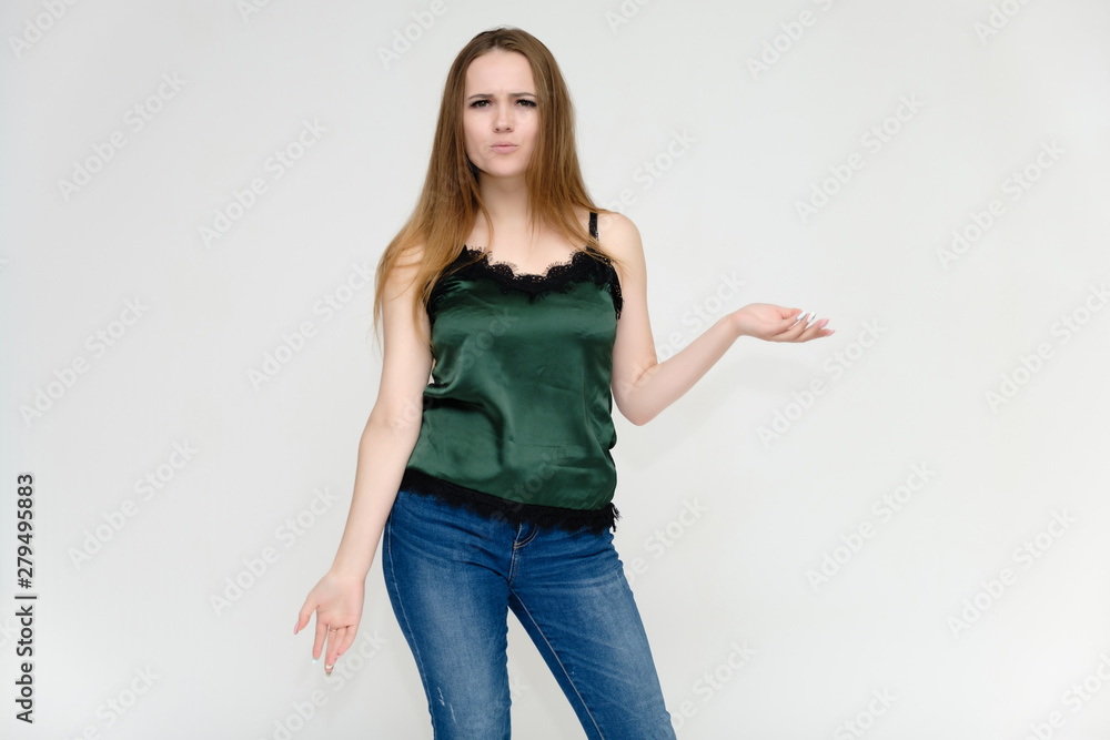Concept portrait above the knee of a pretty girl, a young woman with long beautiful brown hair and a green t-shirt and blue jeans on a white background. In studio in different poses showing emotions. Concept portrait above the knee of a pretty girl, a young woman with long beautiful brown hair and a green t-shirt and blue jeans on a white background. In studio in different poses showing emotions.