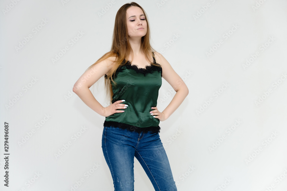 Concept portrait above the knee of a pretty girl, a young woman with long beautiful brown hair and a green t-shirt and blue jeans on a white background. In studio in different poses showing emotions. Concept portrait above the knee of a pretty girl, a young woman with long beautiful brown hair and a green t-shirt and blue jeans on a white background. In studio in different poses showing emotions.