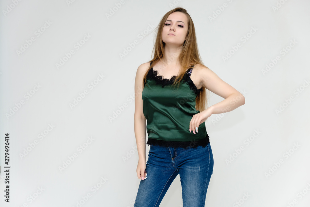 Concept portrait above the knee of a pretty girl, a young woman with long beautiful brown hair and a green t-shirt and blue jeans on a white background. In studio in different poses showing emotions. Concept portrait above the knee of a pretty girl, a young woman with long beautiful brown hair and a green t-shirt and blue jeans on a white background. In studio in different poses showing emotions.