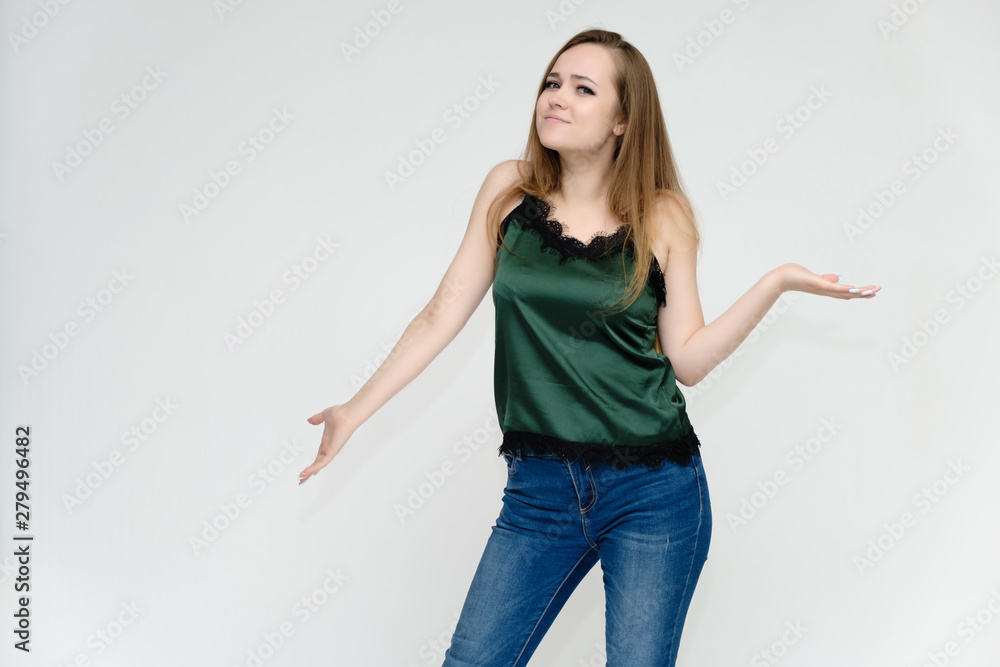 Concept portrait above the knee of a pretty girl, a young woman with long beautiful brown hair and a green t-shirt and blue jeans on a white background. In studio in different poses showing emotions. Concept portrait above the knee of a pretty girl, a young woman with long beautiful brown hair and a green t-shirt and blue jeans on a white background. In studio in different poses showing emotions.