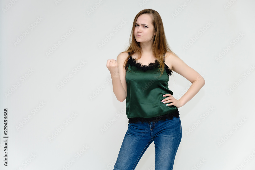 Concept portrait above the knee of a pretty girl, a young woman with long beautiful brown hair and a green t-shirt and blue jeans on a white background. In studio in different poses showing emotions. Concept portrait above the knee of a pretty girl, a young woman with long beautiful brown hair and a green t-shirt and blue jeans on a white background. In studio in different poses showing emotions.