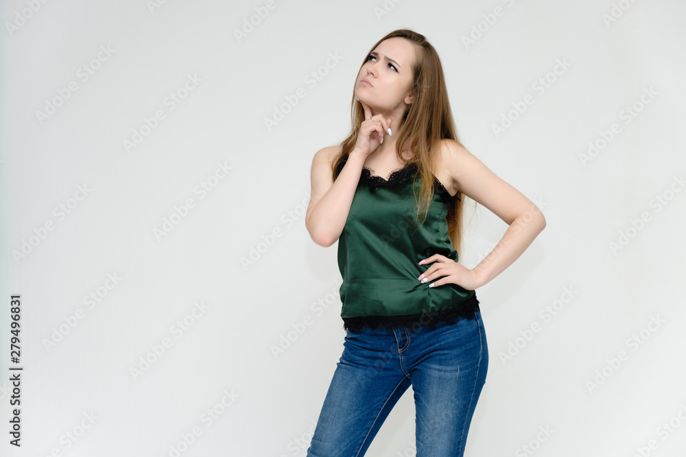 Concept portrait above the knee of a pretty girl, a young woman with long beautiful brown hair and a green t-shirt and blue jeans on a white background. In studio in different poses showing emotions. Concept portrait above the knee of a pretty girl, a young woman with long beautiful brown hair and a green t-shirt and blue jeans on a white background. In studio in different poses showing emotions.