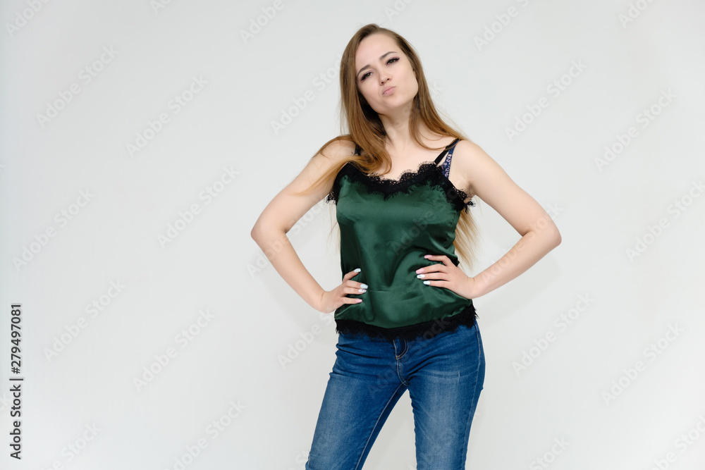 Concept portrait above the knee of a pretty girl, a young woman with long beautiful brown hair and a green t-shirt and blue jeans on a white background. In studio in different poses showing emotions. Concept portrait above the knee of a pretty girl, a young woman with long beautiful brown hair and a green t-shirt and blue jeans on a white background. In studio in different poses showing emotions.
