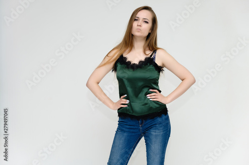 Concept portrait above the knee of a pretty girl, a young woman with long beautiful brown hair and a green t-shirt and blue jeans on a white background. In studio in different poses showing emotions.