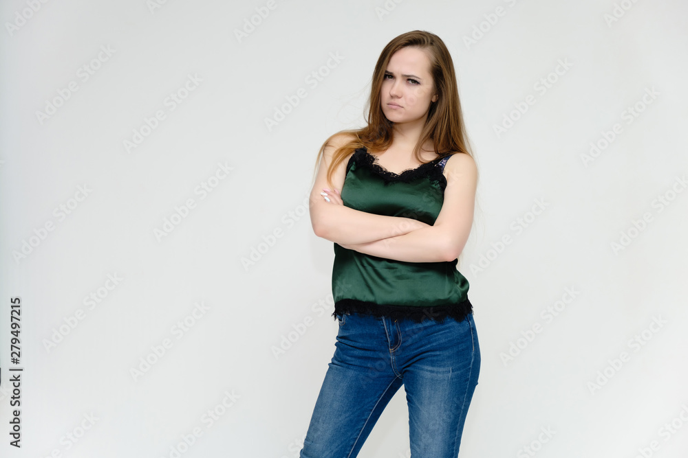 Concept portrait above the knee of a pretty girl, a young woman with long beautiful brown hair and a green t-shirt and blue jeans on a white background. In studio in different poses showing emotions. Concept portrait above the knee of a pretty girl, a young woman with long beautiful brown hair and a green t-shirt and blue jeans on a white background. In studio in different poses showing emotions.