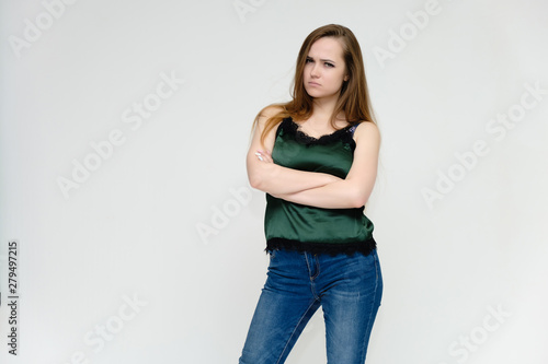 Concept portrait above the knee of a pretty girl, a young woman with long beautiful brown hair and a green t-shirt and blue jeans on a white background. In studio in different poses showing emotions. © Вячеслав Чичаев