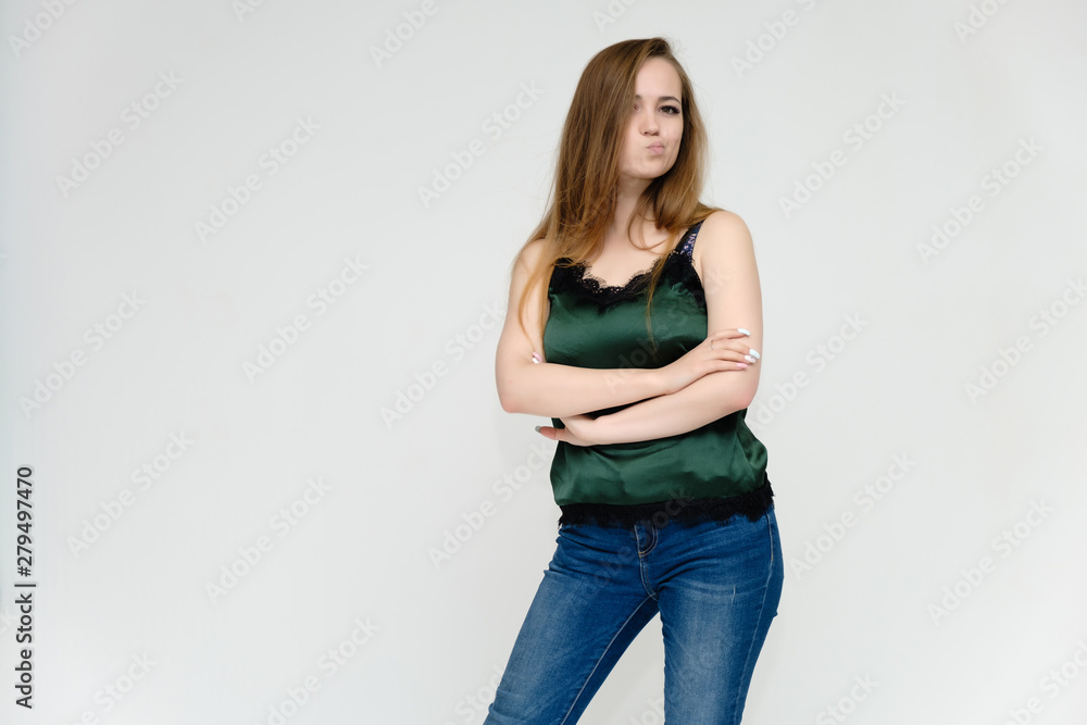 Concept portrait above the knee of a pretty girl, a young woman with long beautiful brown hair and a green t-shirt and blue jeans on a white background. In studio in different poses showing emotions. Concept portrait above the knee of a pretty girl, a young woman with long beautiful brown hair and a green t-shirt and blue jeans on a white background. In studio in different poses showing emotions.