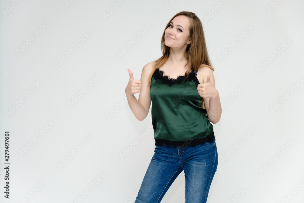 Concept portrait above the knee of a pretty girl, a young woman with long beautiful brown hair and a green t-shirt and blue jeans on a white background. In studio in different poses showing emotions. Concept portrait above the knee of a pretty girl, a young woman with long beautiful brown hair and a green t-shirt and blue jeans on a white background. In studio in different poses showing emotions.