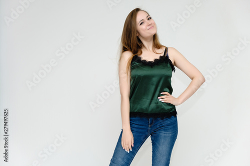 Concept portrait above the knee of a pretty girl, a young woman with long beautiful brown hair and a green t-shirt and blue jeans on a white background. In studio in different poses showing emotions.