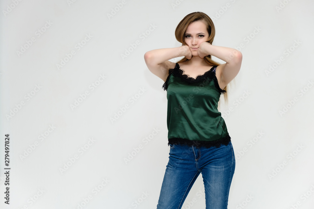 Concept portrait above the knee of a pretty girl, a young woman with long beautiful brown hair and a green t-shirt and blue jeans on a white background. In studio in different poses showing emotions. Concept portrait above the knee of a pretty girl, a young woman with long beautiful brown hair and a green t-shirt and blue jeans on a white background. In studio in different poses showing emotions.