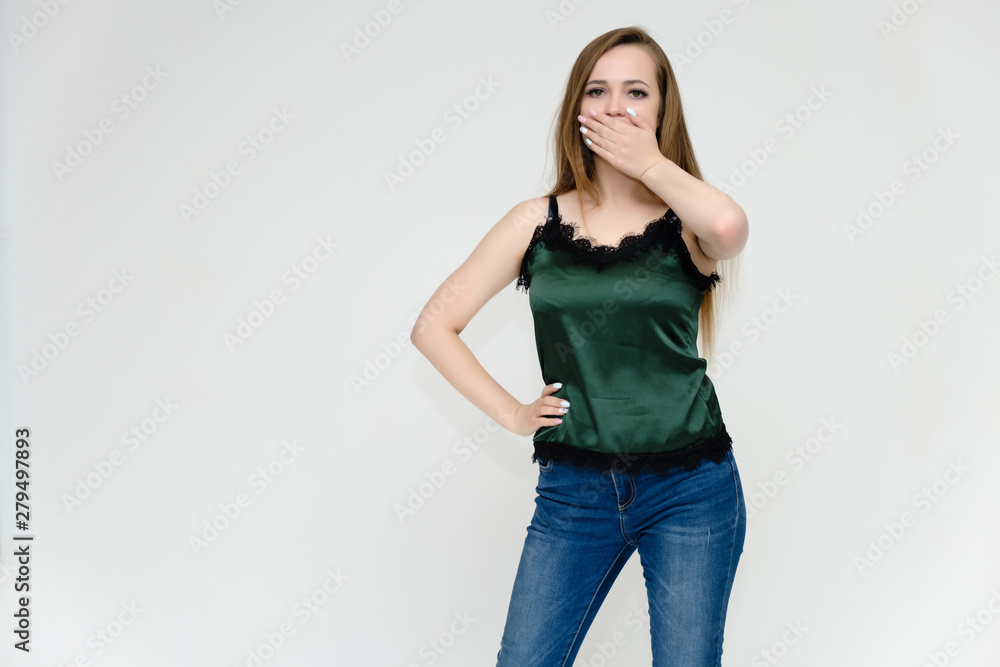 Concept portrait above the knee of a pretty girl, a young woman with long beautiful brown hair and a green t-shirt and blue jeans on a white background. In studio in different poses showing emotions. Concept portrait above the knee of a pretty girl, a young woman with long beautiful brown hair and a green t-shirt and blue jeans on a white background. In studio in different poses showing emotions.