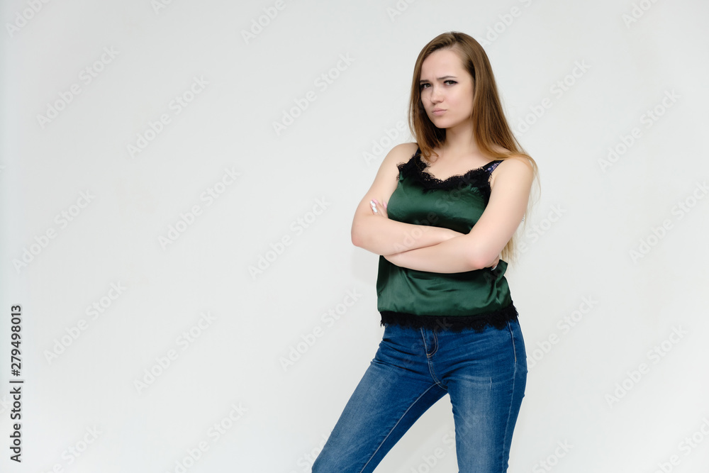 Concept portrait above the knee of a pretty girl, a young woman with long beautiful brown hair and a green t-shirt and blue jeans on a white background. In studio in different poses showing emotions. Concept portrait above the knee of a pretty girl, a young woman with long beautiful brown hair and a green t-shirt and blue jeans on a white background. In studio in different poses showing emotions.