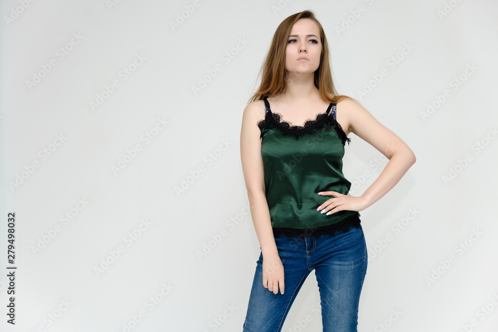 Concept portrait above the knee of a pretty girl, a young woman with long beautiful brown hair and a green t-shirt and blue jeans on a white background. In studio in different poses showing emotions. Concept portrait above the knee of a pretty girl, a young woman with long beautiful brown hair and a green t-shirt and blue jeans on a white background. In studio in different poses showing emotions.
