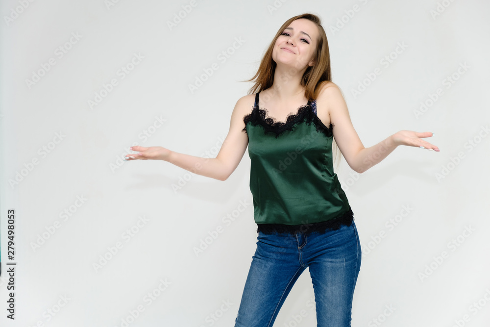 Concept portrait above the knee of a pretty girl, a young woman with long beautiful brown hair and a green t-shirt and blue jeans on a white background. In studio in different poses showing emotions. Concept portrait above the knee of a pretty girl, a young woman with long beautiful brown hair and a green t-shirt and blue jeans on a white background. In studio in different poses showing emotions.