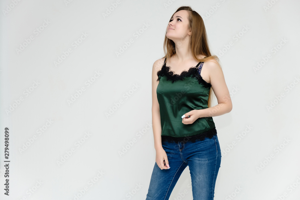 Concept portrait above the knee of a pretty girl, a young woman with long beautiful brown hair and a green t-shirt and blue jeans on a white background. In studio in different poses showing emotions. Concept portrait above the knee of a pretty girl, a young woman with long beautiful brown hair and a green t-shirt and blue jeans on a white background. In studio in different poses showing emotions.