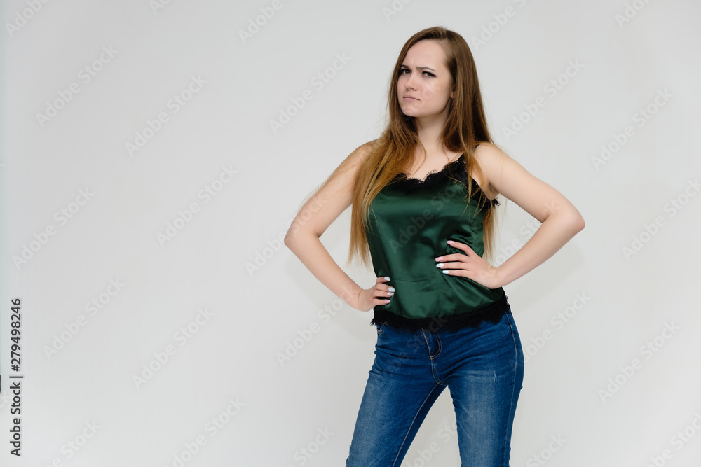Concept portrait above the knee of a pretty girl, a young woman with long beautiful brown hair and a green t-shirt and blue jeans on a white background. In studio in different poses showing emotions. Concept portrait above the knee of a pretty girl, a young woman with long beautiful brown hair and a green t-shirt and blue jeans on a white background. In studio in different poses showing emotions.