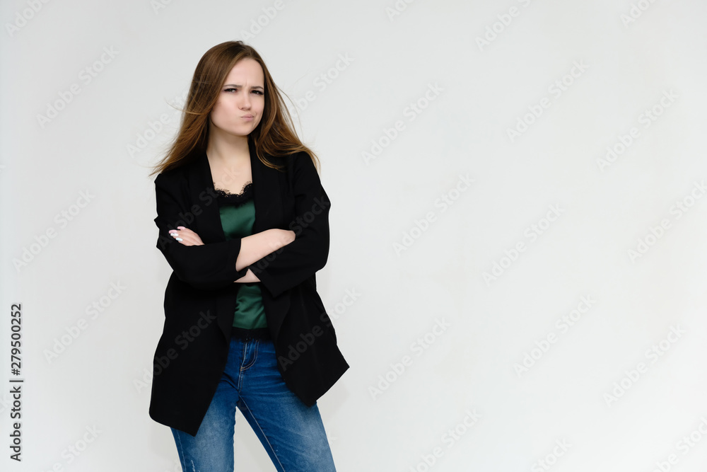 Concept portrait above the knee of a pretty girl, a young woman with long beautiful brown hair and a black jacket and blue jeans on a white background. In studio in different poses showing emotions. Concept portrait above the knee of a pretty girl, a young woman with long beautiful brown hair and a black jacket and blue jeans on a white background. In studio in different poses showing emotions.