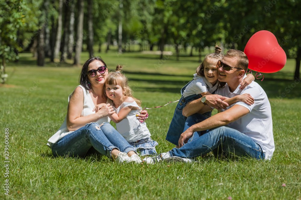 Happy young family have a rest in the park sitting on a grass Happy young family have a rest in the park sitting on a grass