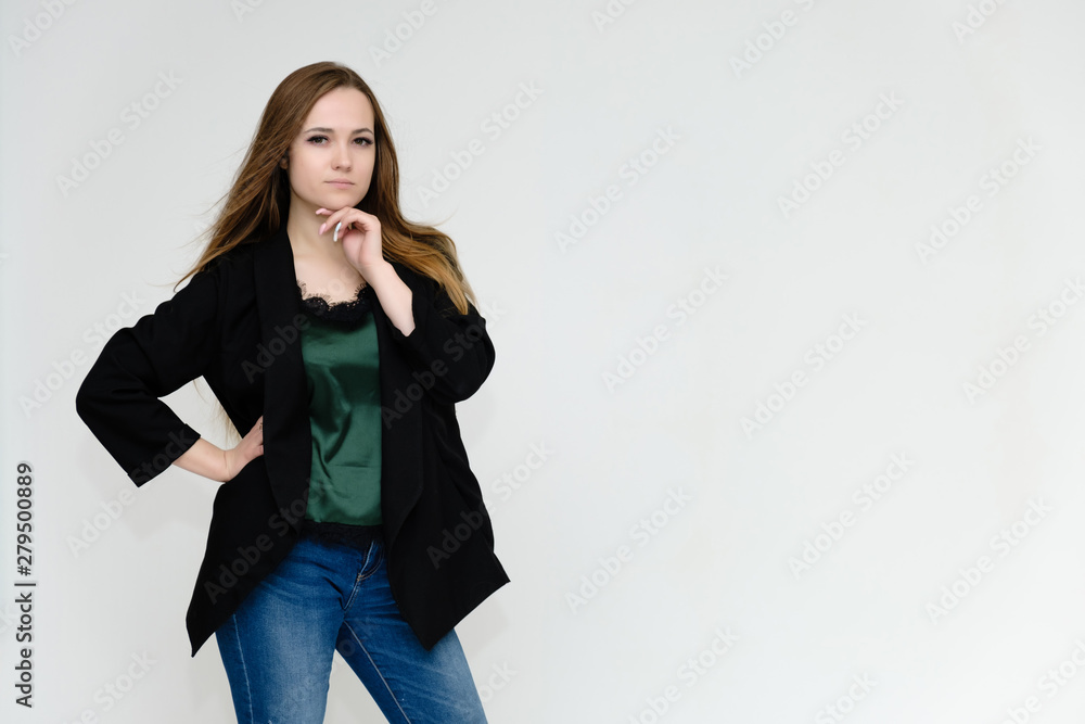 Concept portrait above the knee of a pretty girl, a young woman with long beautiful brown hair and a black jacket and blue jeans on a white background. In studio in different poses showing emotions. Concept portrait above the knee of a pretty girl, a young woman with long beautiful brown hair and a black jacket and blue jeans on a white background. In studio in different poses showing emotions.